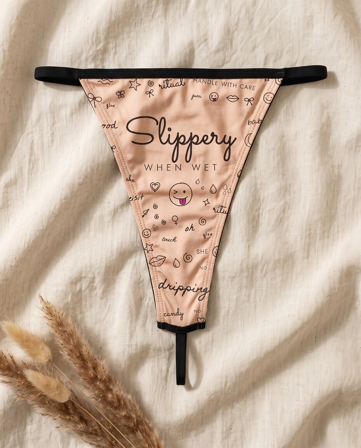 Flat lay of the She. Slippery When Wet thong showing the full doodle print and black trim