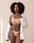Model wearing the Slippery When Wet printed thong with a nude ribbed bralette and white linen shirt